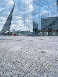 some kind of glass building near a brick paved area with a red fire hydrant