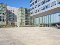 an empty square in front of some very tall buildings with windows to either side of it