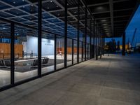 the inside of a building that has glass walls and benches outside it at night in an urban area