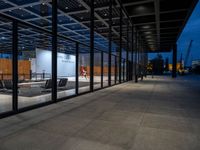 the inside of a building that has glass walls and benches outside it at night in an urban area