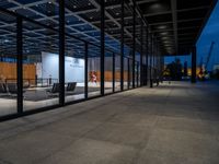 the inside of a building that has glass walls and benches outside it at night in an urban area