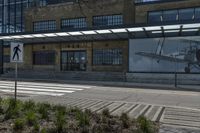 there are two airplanes displayed on the building wall near the crosswalk and sidewalk in front of the building