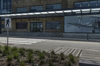 there are two airplanes displayed on the building wall near the crosswalk and sidewalk in front of the building