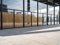 an empty sidewalk between two large windows that have glass panels on them to provide privacy