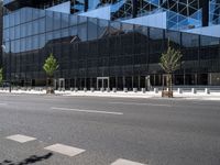 the city has a glass building with trees on each side of it and benches outside