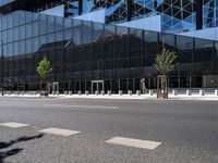 the city has a glass building with trees on each side of it and benches outside