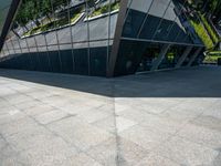 a large silver building with many windows and mirrors on it's face near a sidewalk