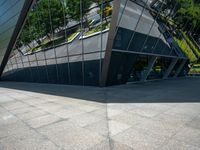 a large silver building with many windows and mirrors on it's face near a sidewalk