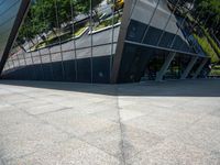 a large silver building with many windows and mirrors on it's face near a sidewalk