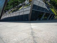 a large silver building with many windows and mirrors on it's face near a sidewalk