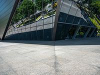 a large silver building with many windows and mirrors on it's face near a sidewalk