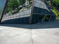 a large silver building with many windows and mirrors on it's face near a sidewalk