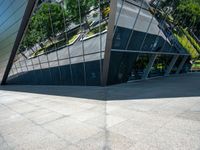 a large silver building with many windows and mirrors on it's face near a sidewalk