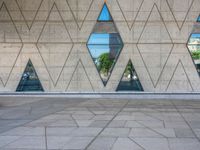 an empty concrete floor with three triangular windows and some trees in the background that is all around