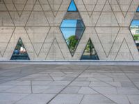 an empty concrete floor with three triangular windows and some trees in the background that is all around