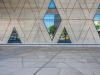 an empty concrete floor with three triangular windows and some trees in the background that is all around