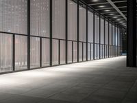 a hallway with multiple windows and sheered walls next to some tall buildings and lights