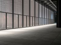 a hallway with multiple windows and sheered walls next to some tall buildings and lights