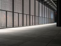 a hallway with multiple windows and sheered walls next to some tall buildings and lights