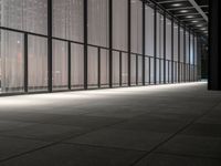 a hallway with multiple windows and sheered walls next to some tall buildings and lights