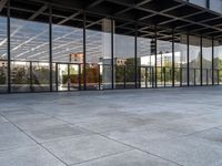 an empty public park has large glass windows on both sides and walls with seatings on each side