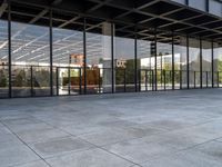 an empty public park has large glass windows on both sides and walls with seatings on each side