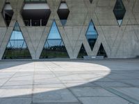 the shadow of the person is on the ground by a building with triangular windows on the side