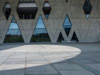 the shadow of the person is on the ground by a building with triangular windows on the side