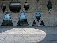 the shadow of the person is on the ground by a building with triangular windows on the side