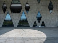 the shadow of the person is on the ground by a building with triangular windows on the side