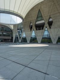 a building with an outdoor space and concrete walls and a circular design on the outside