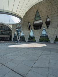 a building with an outdoor space and concrete walls and a circular design on the outside