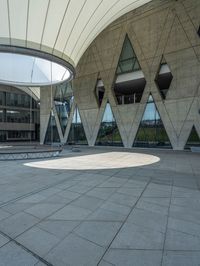 a building with an outdoor space and concrete walls and a circular design on the outside