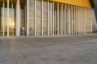 large columns inside the outside of a building with a large sun rising behind them and reflecting into the glass window windows