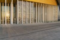 large columns inside the outside of a building with a large sun rising behind them and reflecting into the glass window windows