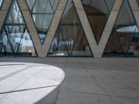 an empty walkway outside a large building with glass panels on the walls and many windows