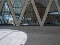 an empty walkway outside a large building with glass panels on the walls and many windows