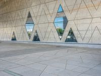 a person walking in front of an office building with windows and triangular designs on the facade