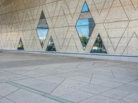 a person walking in front of an office building with windows and triangular designs on the facade