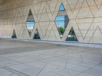 a person walking in front of an office building with windows and triangular designs on the facade