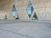 a person walking in front of an office building with windows and triangular designs on the facade