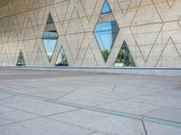 a person walking in front of an office building with windows and triangular designs on the facade