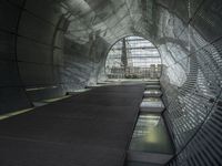 an escalator in a building with glass walls and metal roofing is viewed by several people