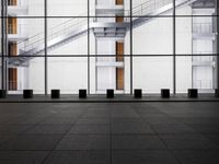 a glass and concrete building with steps leading up into the ceiling in front of the stairs