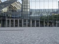 the reflection of the glass walls is in the glass structure behind the benches and man with an umbrella