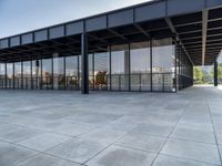 the modern building has glass walls with iron mesh on it's roof, surrounded by stone tile