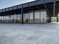 the modern building has glass walls with iron mesh on it's roof, surrounded by stone tile