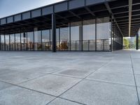 the modern building has glass walls with iron mesh on it's roof, surrounded by stone tile