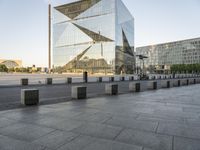 a very tall building on a busy street in europe with glass windows and concrete pillars