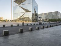 a very tall building on a busy street in europe with glass windows and concrete pillars